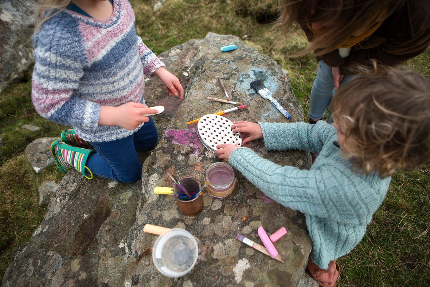 Children playing with chalks on a rock